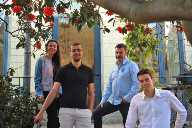 alt - Fotografia da família Lestuzzi em frente do seu restaurante de cozinha francesa num dia de sol com as camélias em flor