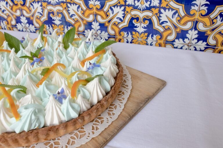 alt - Precise view of the double meringue lemon tart, lemon and orange zest and borage